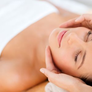 health, beauty, people and relaxation concept - beautiful woman in spa salon getting face treatment